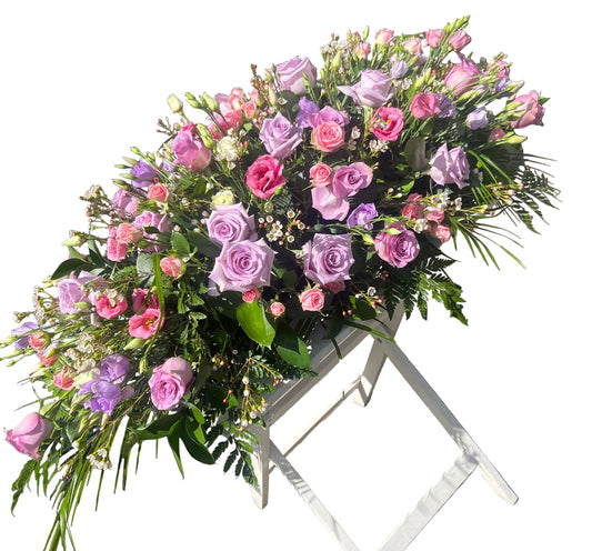Large spray with pink and lavender roses with green foliage 
